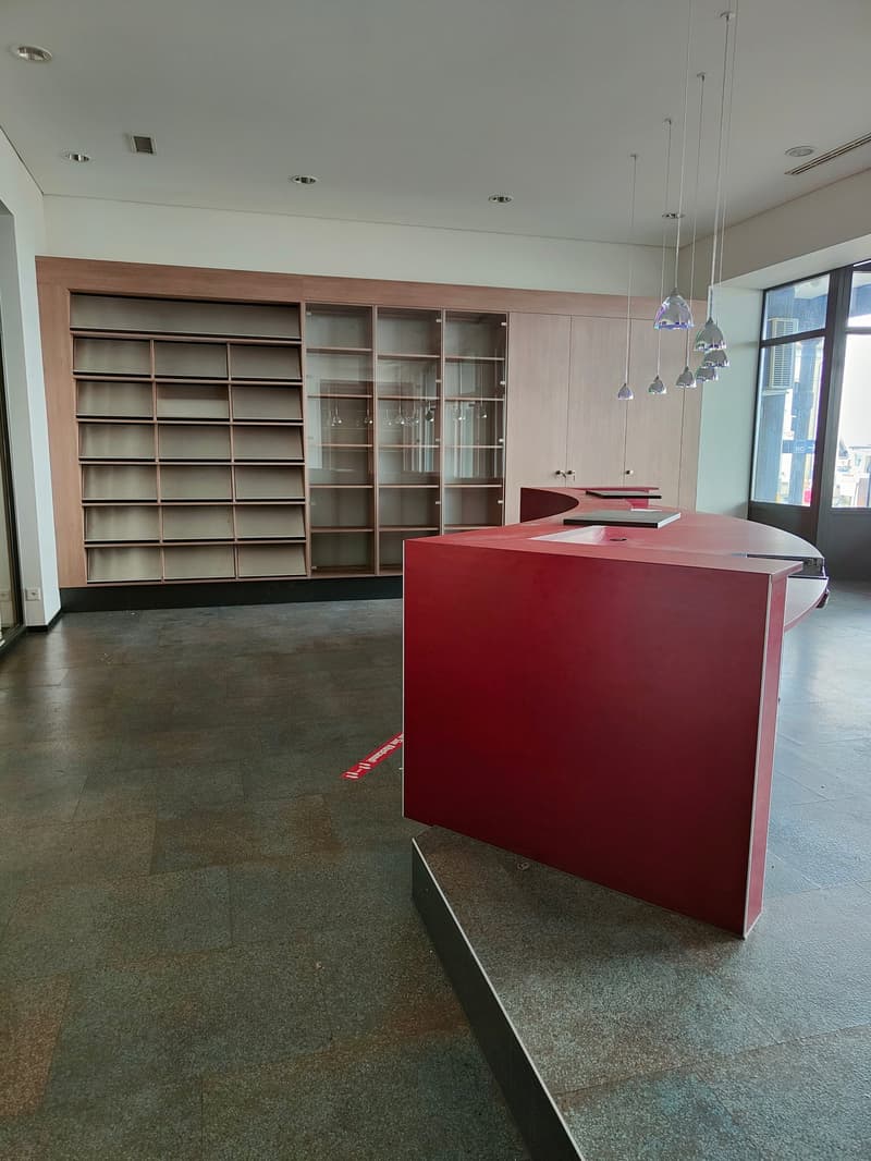 empty room, wooden cabinets, glass shelves, red desk, glass door, gray floor, large window