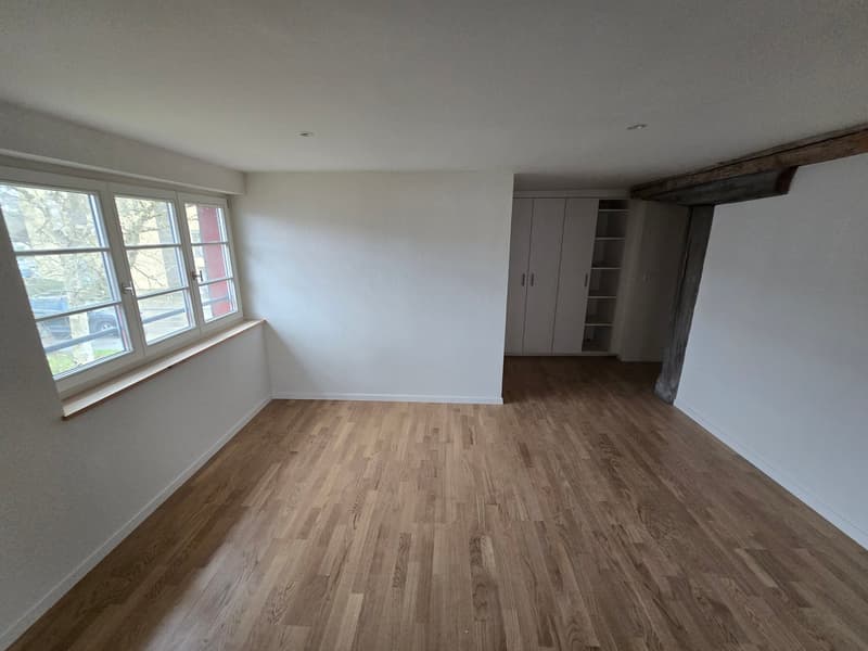 Empty room with white walls, wooden floors, a window, and a closet