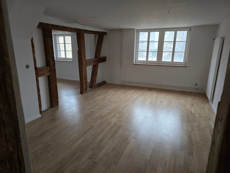 Hardwood floor, wooden beams, windows, empty room