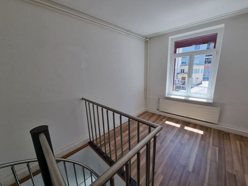 white walls, wooden floor, spiral staircase, window with white frame