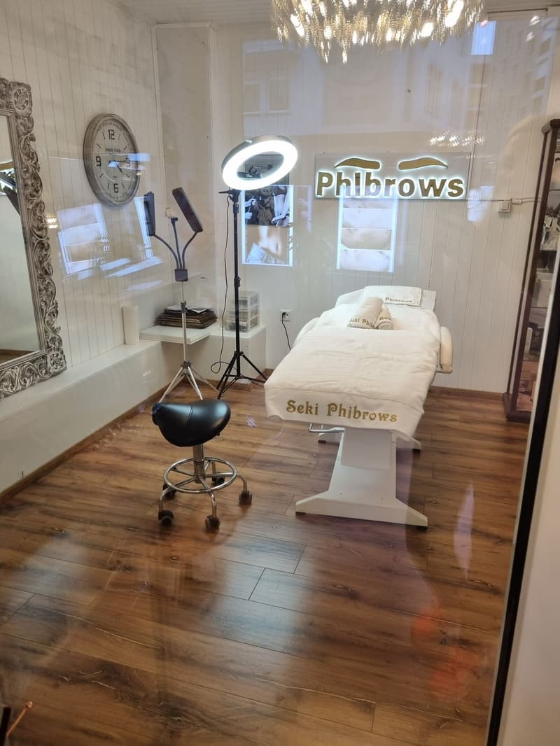 Interior with wooden floor, white walls, mirror, clock, lamp, beauty chair, bed, towels