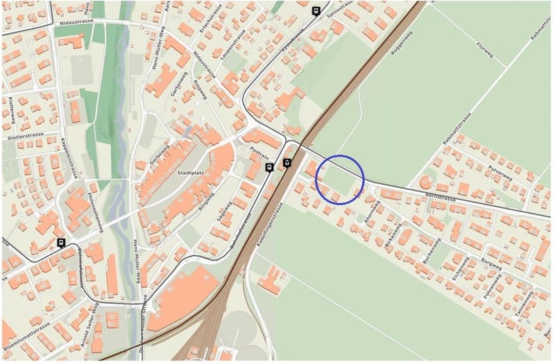This is a detailed map of a town or city, showing various streets, buildings, and infrastructure. The map is centered around a train station or public transportation hub, with a parking area highlighted in the blue circle.