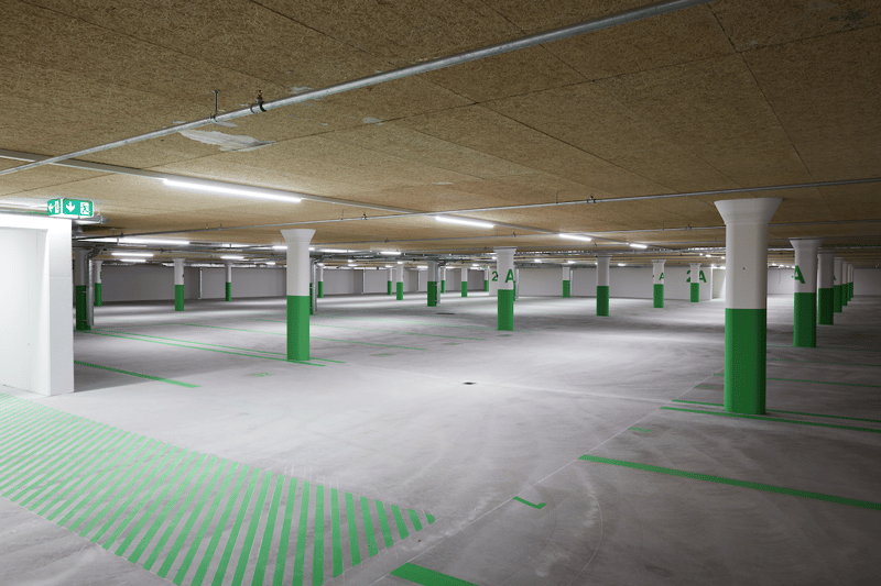 Parking facility with white walls, concrete floor, columns, emergency exits