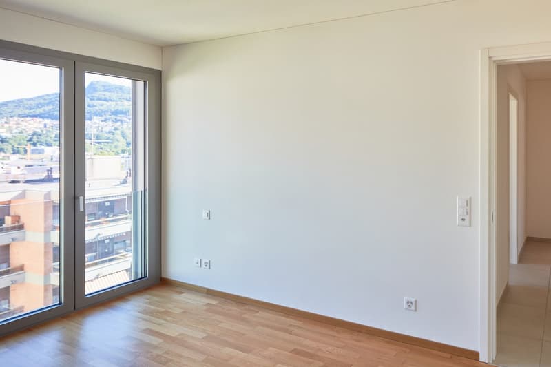 empty room, large windows, wooden floor, white walls, power outlets