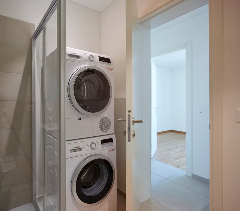 Laundry room with stacked washing machine and dryer, glass door, tiled floor
