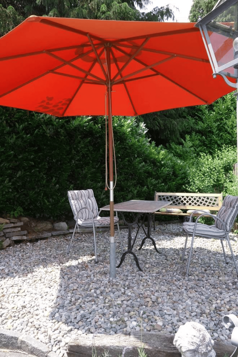 outdoor table and chairs under a large orange umbrella