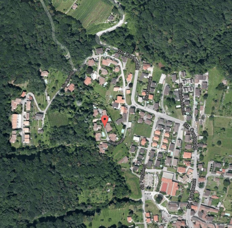 Aerial view of a neighborhood with residential buildings, green trees, and surrounding landscapes