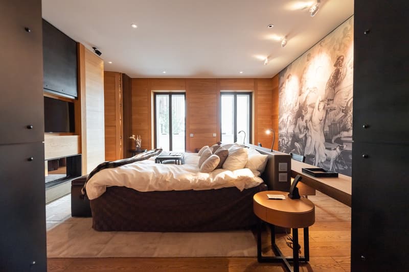 large double bed with lots of pillows, fireplace, wall-mounted TV, modern decor