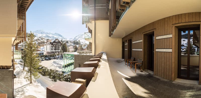 Wooden exterior walls, snowy background, chairs near the entrance, balcony