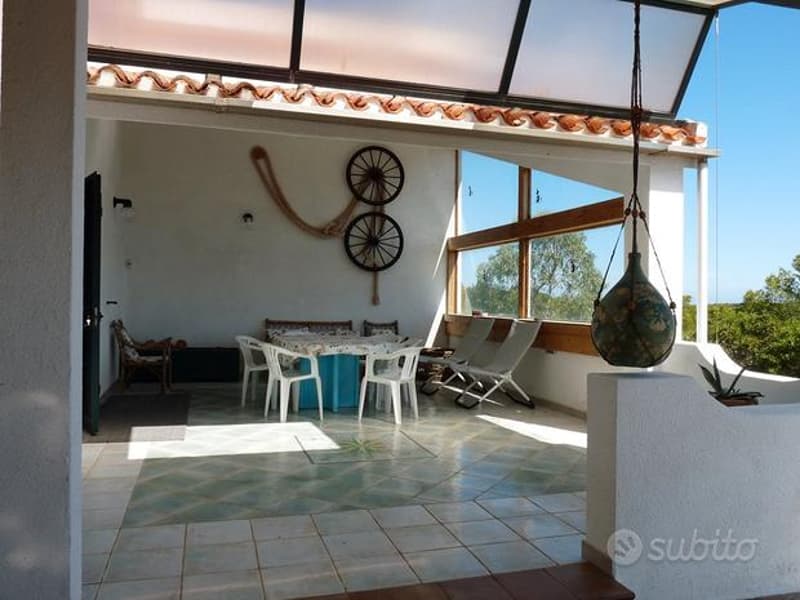 covered seating area, white chairs, blue table, decorative items, tiled floor, large windows
