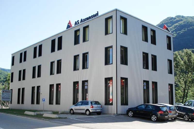large white building, 4 stories, multiple windows, multiple cars parked outside