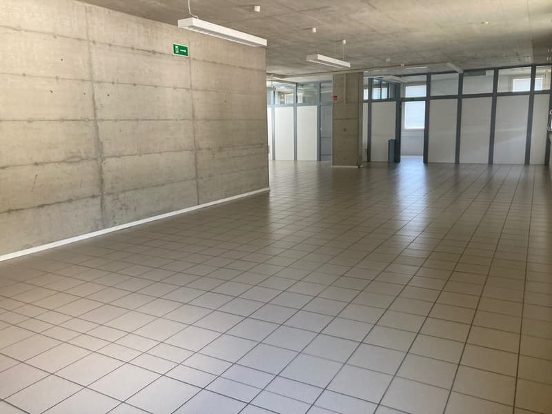 large empty room, tiled floor, large windows, pillar, trash bin