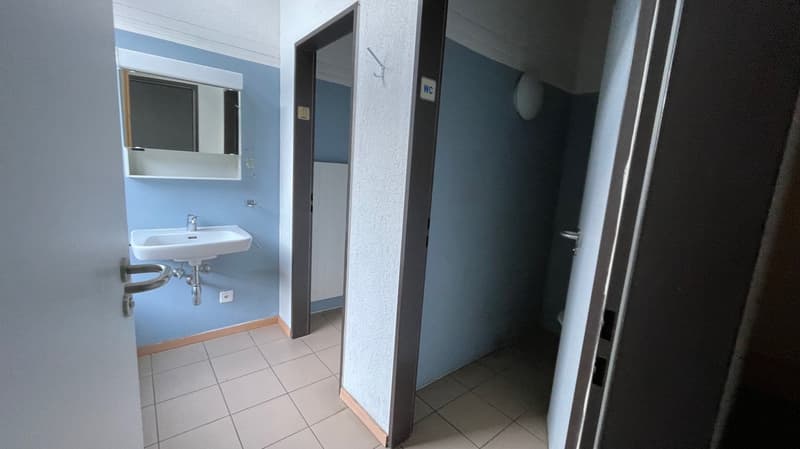 white sink, wall-mounted mirror, blue walls, white tiled floor, power outlet, mirror with mirror frame, two doors
