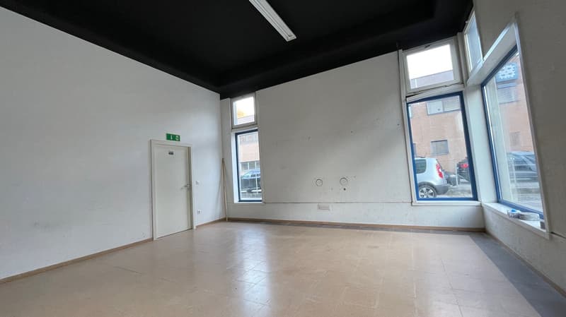 Empty room with tiled floor, white walls, and three windows. There is a white door at the back.