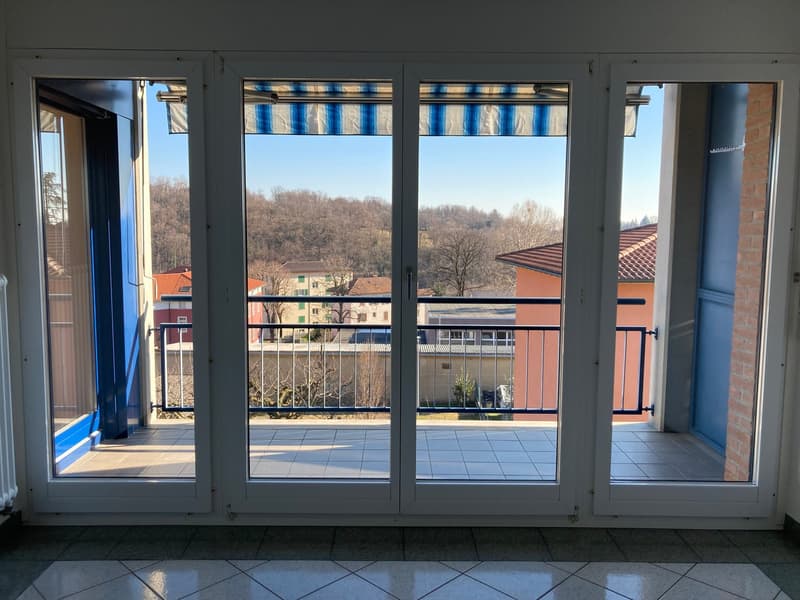 Sliding glass doors, balcony, metal railings, tiled floor, tree and building view
