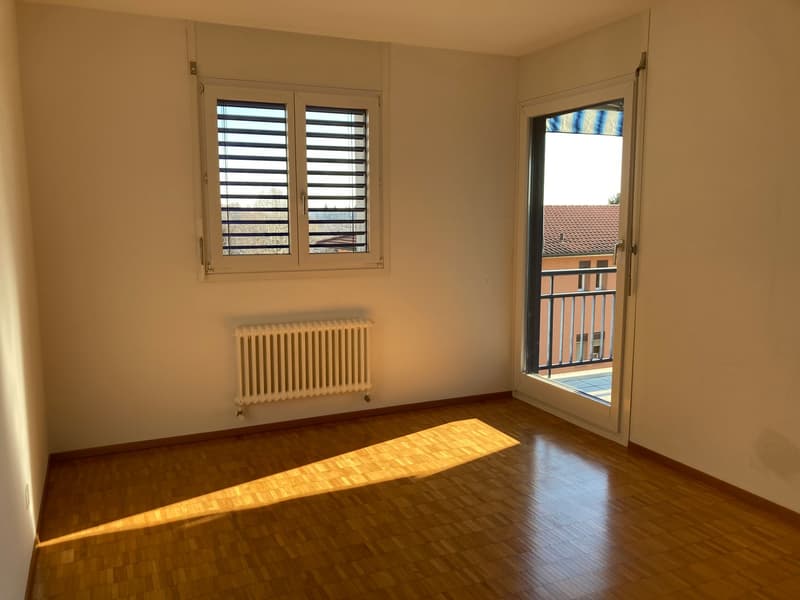 empty room, wooden floor, white walls, white radiator, double glass door leading to balcony