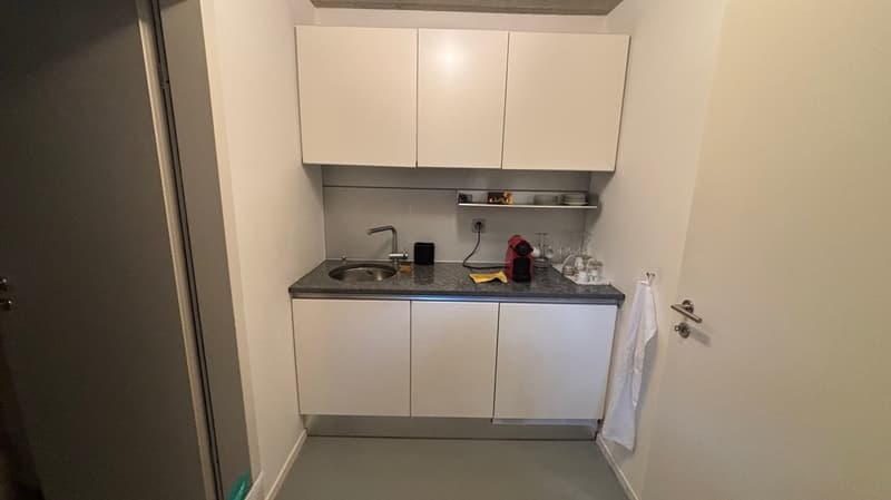 Small kitchen, white cabinets, gray countertop, under cabinet drawers, sink, faucet, coffee maker, power outlet, plates, cups, glasses