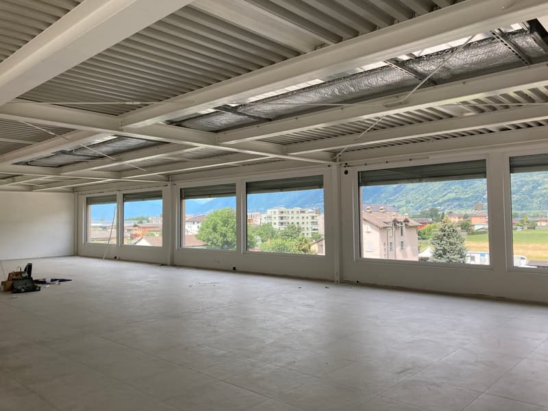 Empty room with large windows, tiled floor, metal ceiling, and a view of the mountains
