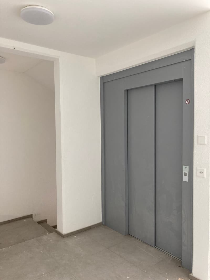 elevator, white walls, gray floor, white ceiling, light fixtures