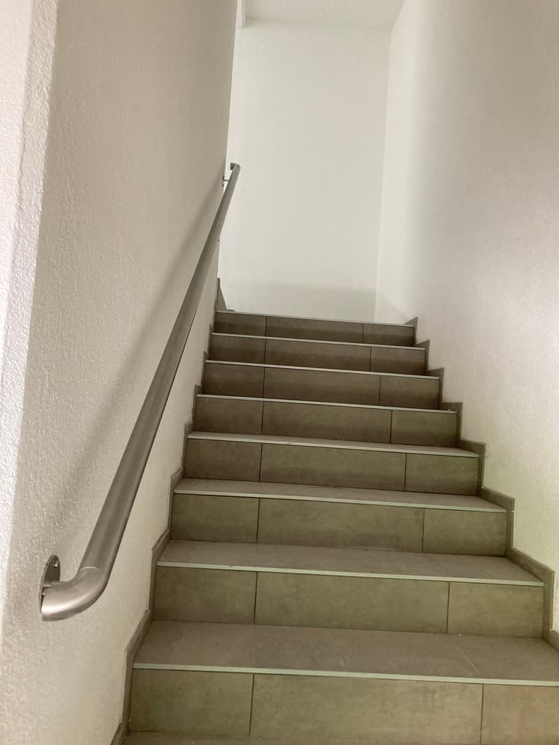 tiled steps, metal handrail, white walls