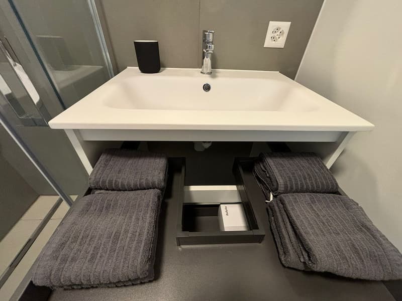 Bathroom sink, drawers under sink, three towels on drawers