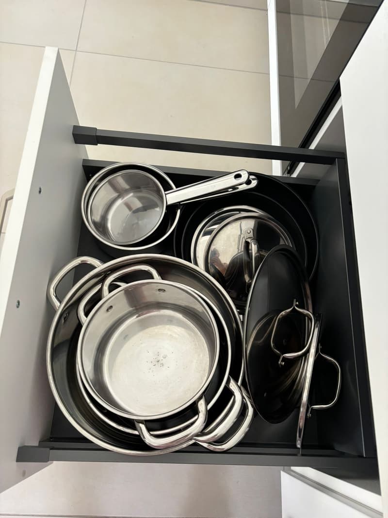 Stainless steel pots and pans inside drawer.