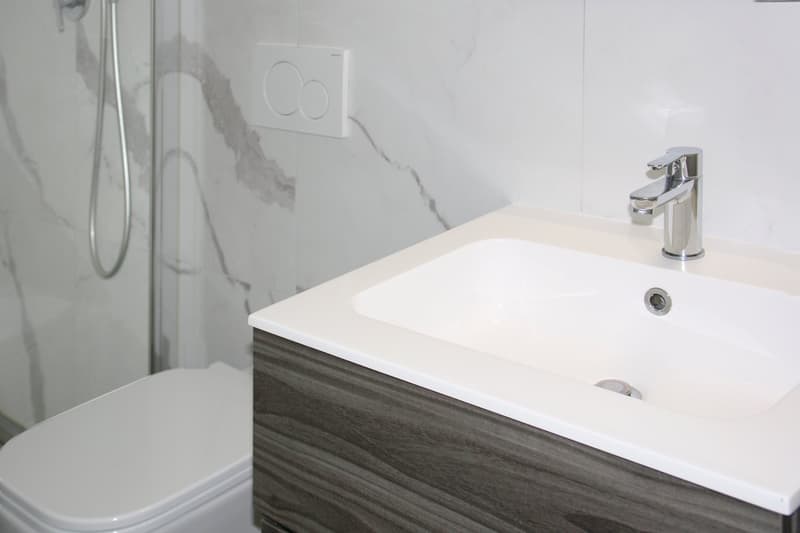 Modern white tiled bathroom with shower and sink