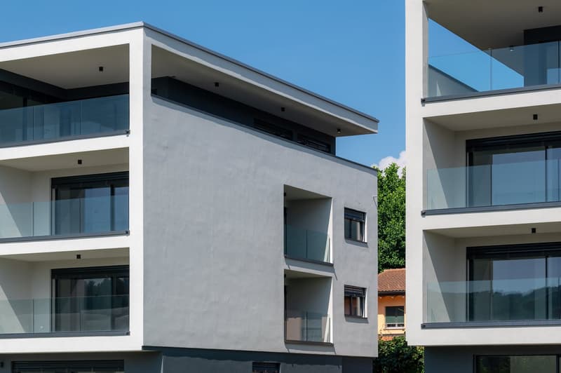 Modern multistory building, glass balconies on each floor, white walls, glass windows