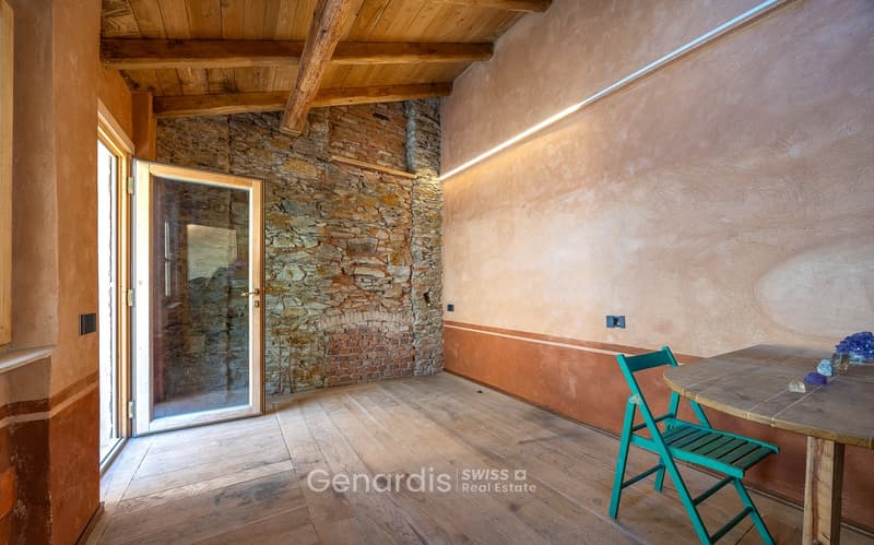 wooden floor, stone wall, fireplace, glass door, wooden table, green chair