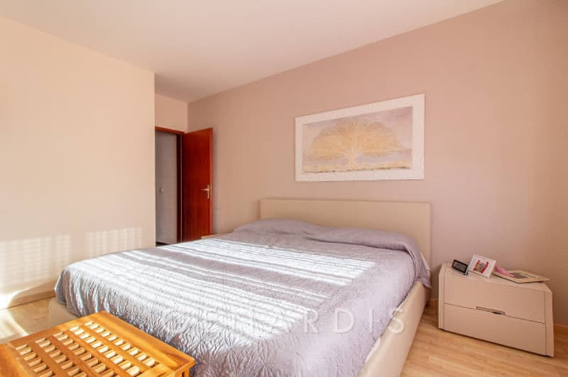 Bedroom with bed, nightstand, wooden footboard, picture frame on wall, wooden door