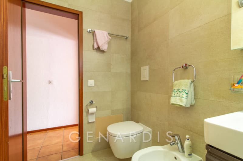 white toilet, white sink, towel rack, wooden door, tiled floor