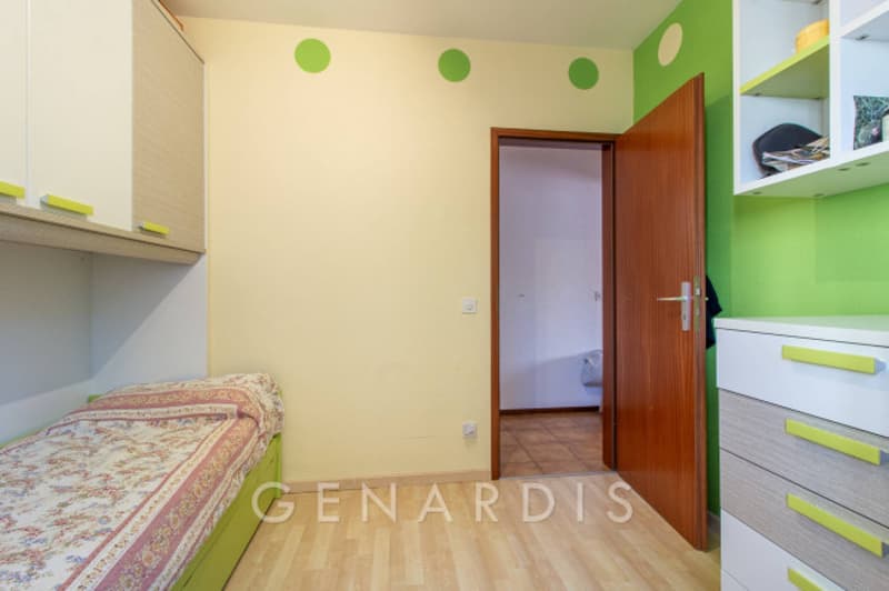 single bed, wooden floor, green wall with white dots, wooden door, white and green cabinets, drawers