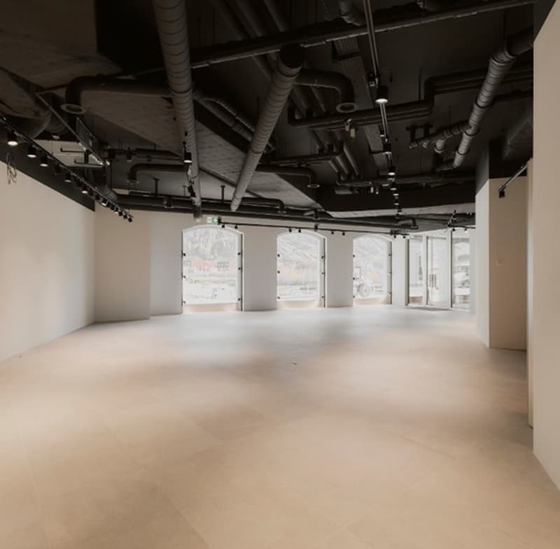Large open space with exposed ceiling, concrete floor, and large windows providing natural light. The space appears to be an unfinished office or commercial area ready for customization and tenant build-out.