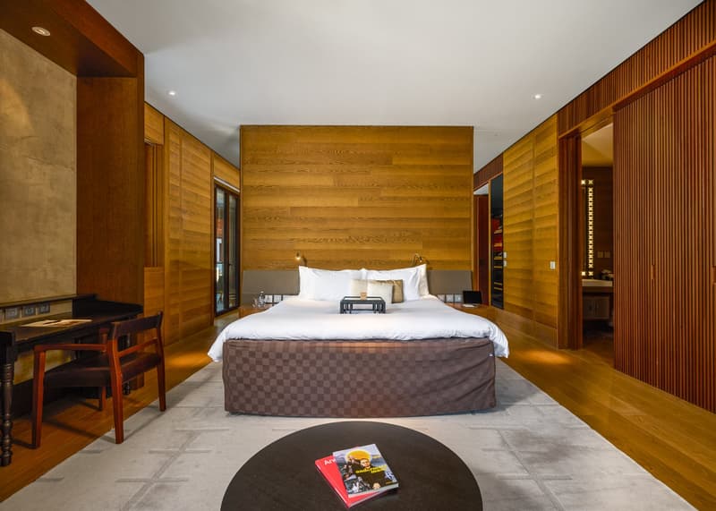large bed, wooden walls, desk, chair, carpet, table with magazines