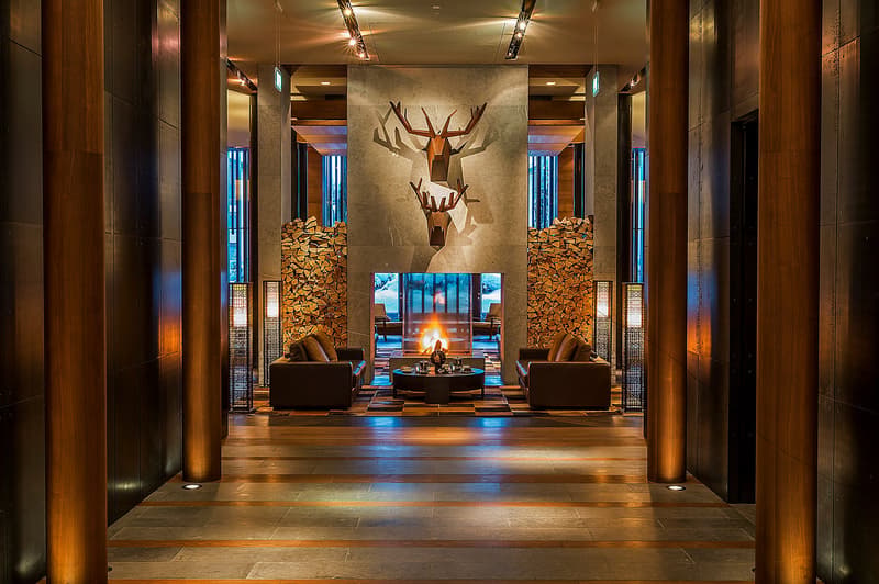 wooden pillars, fireplace, two couches, coffee table, deer head wall art