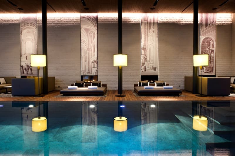 Indoor pool, lounge area with daybeds, fireplaces, lamps, and decorative wall murals