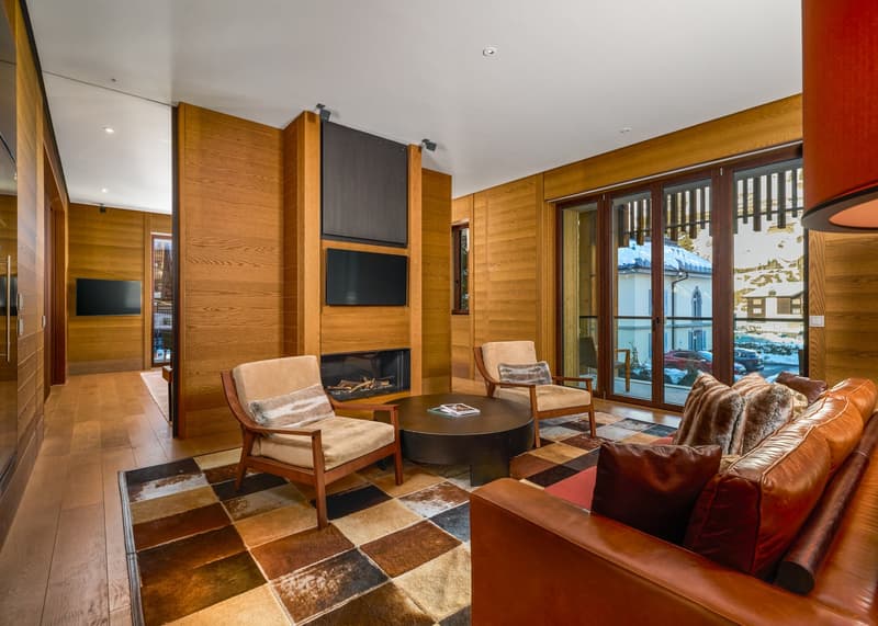 wooden walls, fireplace, large windows, leather couch, coffee table, armchairs, rug