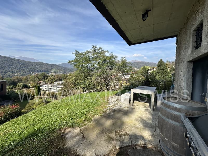stone balcony with a table and benches, green lawn, mountain view