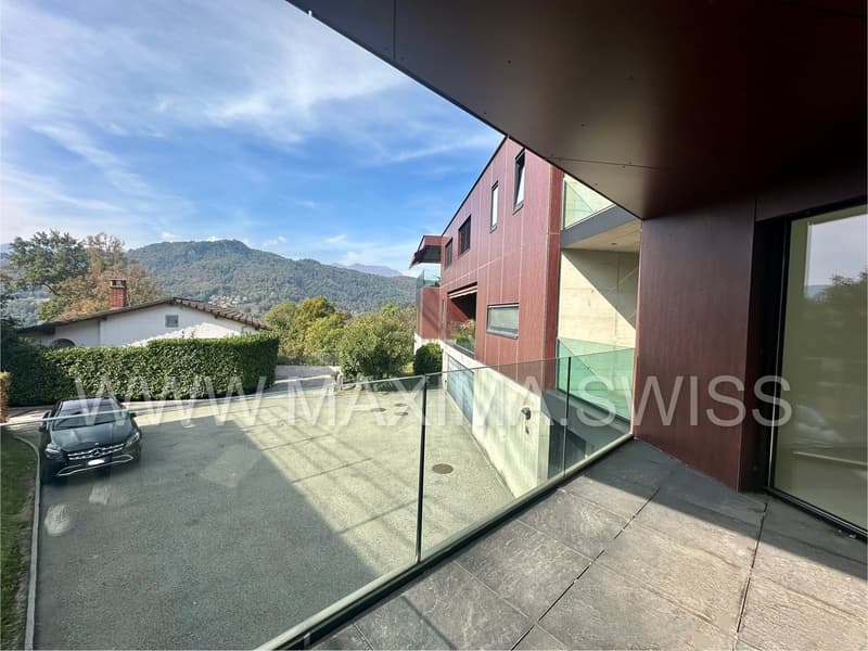 exterior view with balcony, driveway with car, building with glass windows, distant mountain