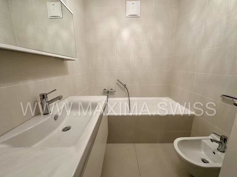 Modern bathroom with a bathtub, sink, and mirror; white tiles