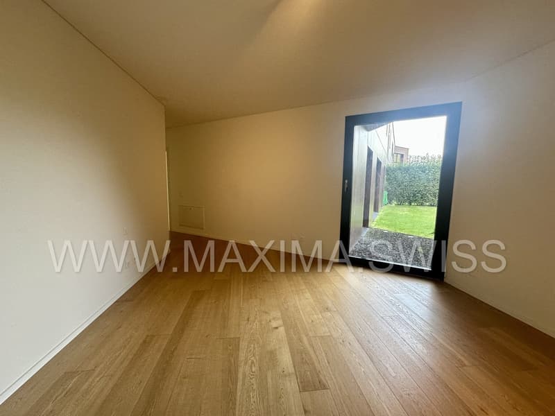 Empty room with wooden floors, glass door, and window leading to balcony.