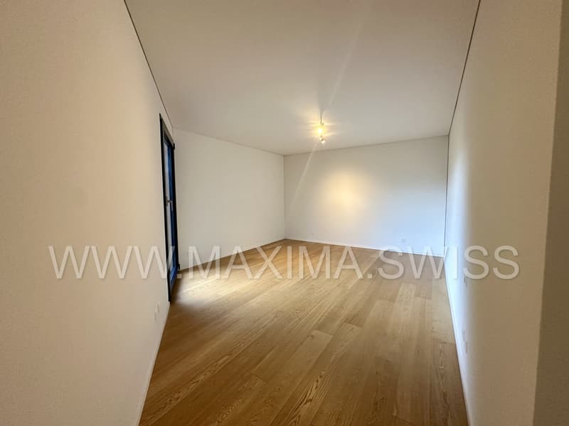 Spacious room with wooden floors, white walls, and a single light fixture on the ceiling.