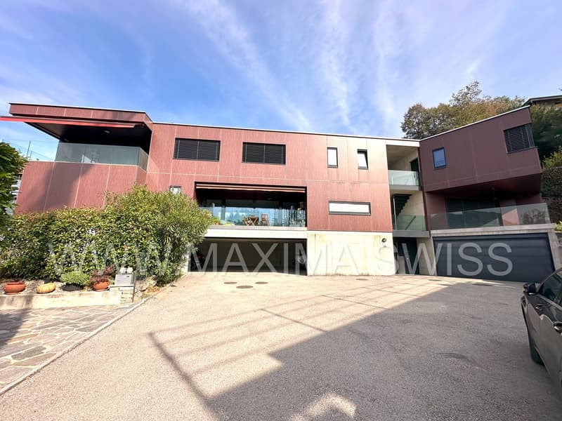 Modern residential building, 3 stories, red brick, large windows, garage, parking space