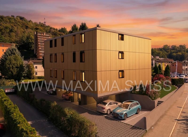An apartment building with a parking area where three cars are parked.