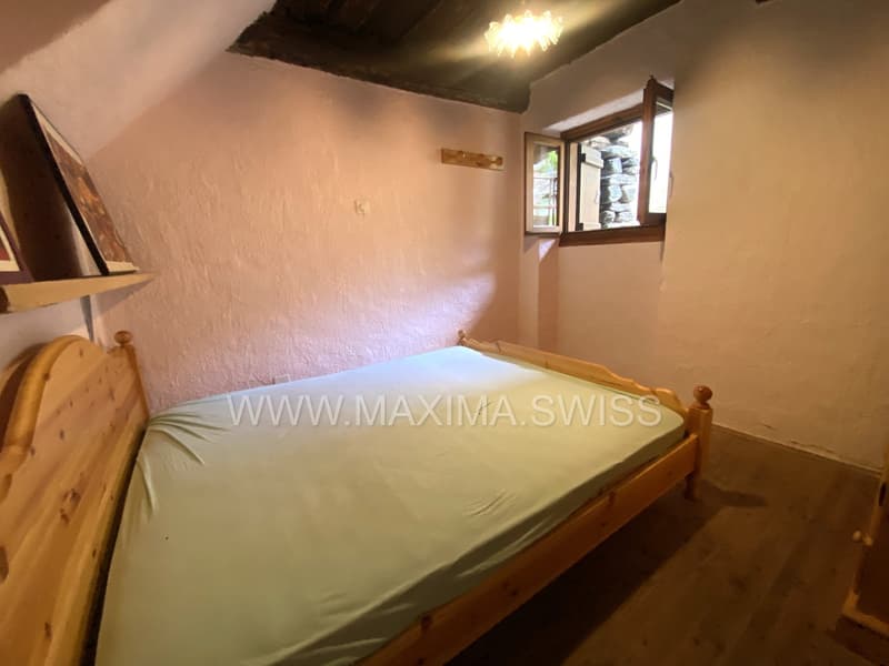 wooden bed, clean sheet, wooden headboard, white walls, small window