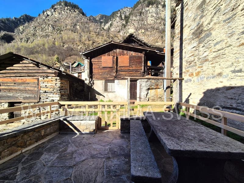 stone wall house, wooden benches, wooden fence, house in the background, mountain view