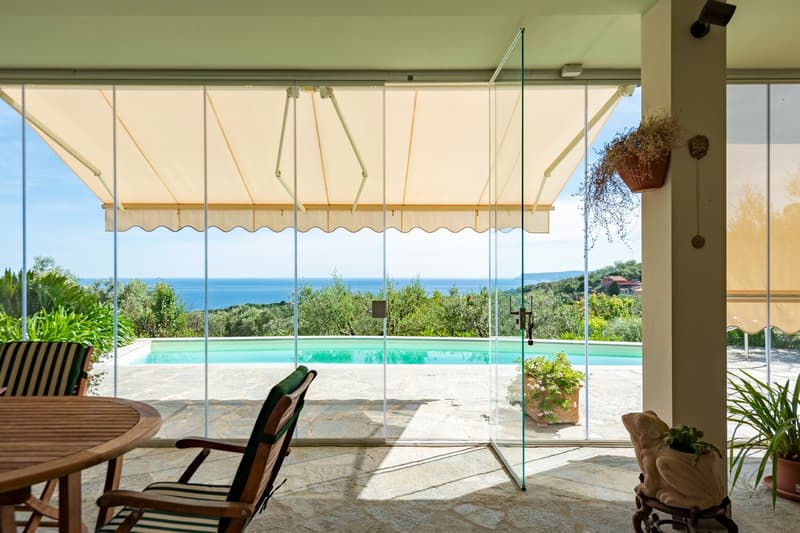 glass doors, wooden table, chairs, swimming pool, sea view