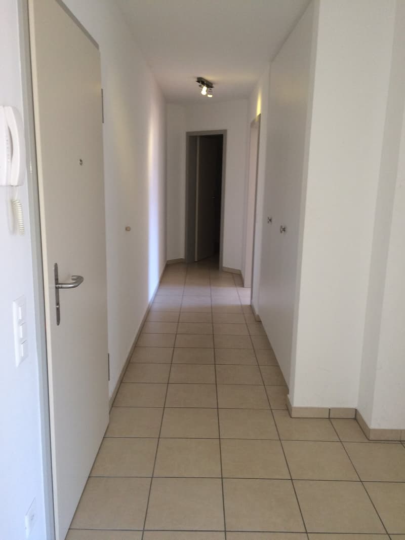 tiled floor, white walls, hallway lighting, open door, light coming from the room