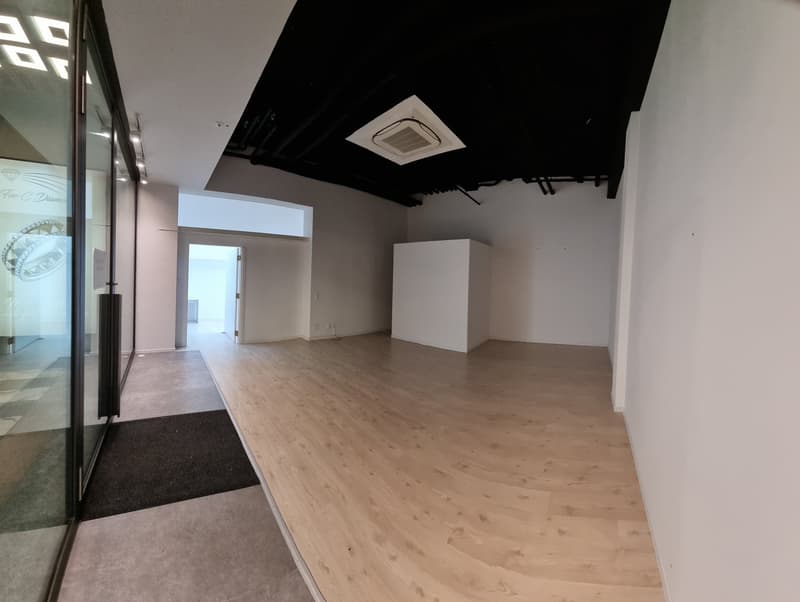 Empty room with wooden floor, white walls, glass door, black carpet, white cabinet, air conditioning unit on ceiling