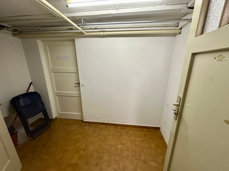 Empty room with white walls, tiled floor, a door, and a power outlet.